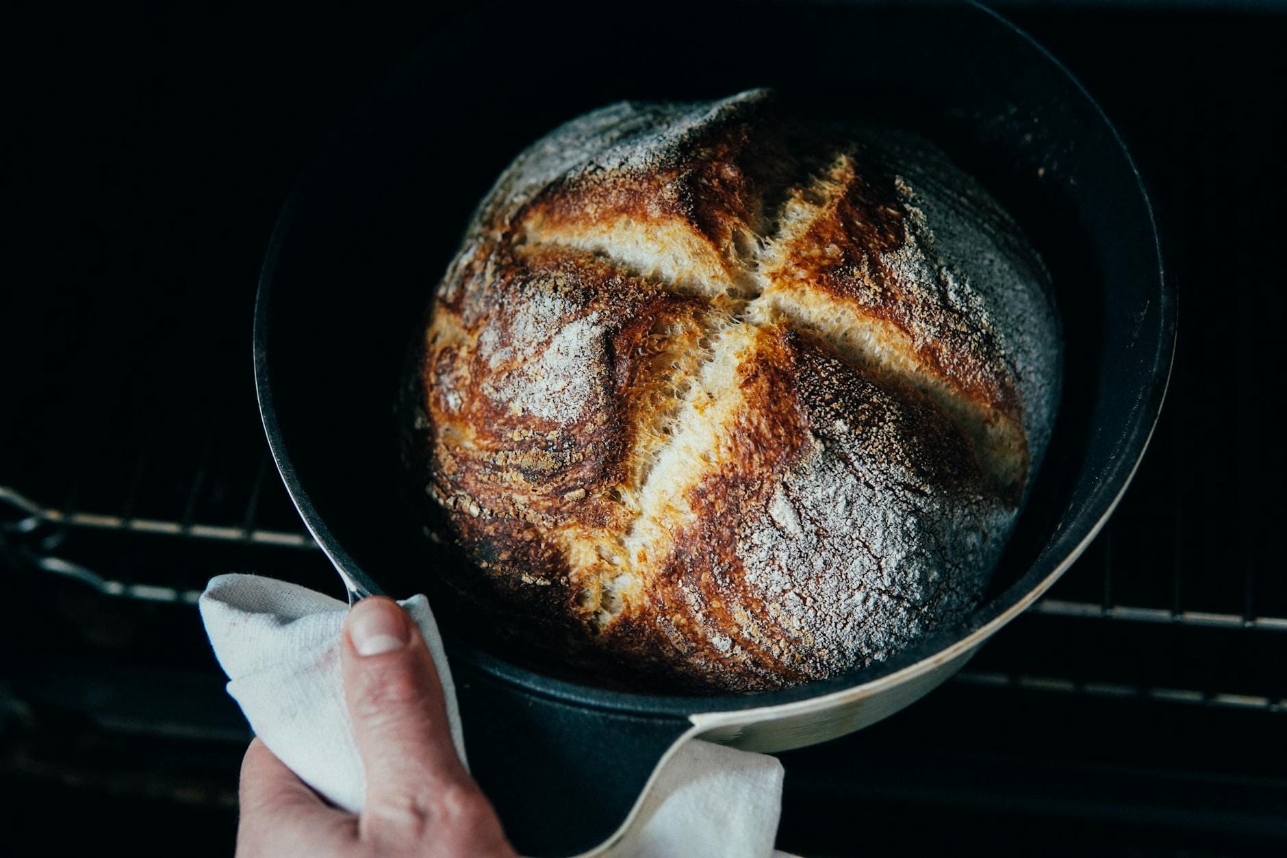 Piekarz wyjmuje z piekarnika świeży, chrupiący chleb na zakwasie