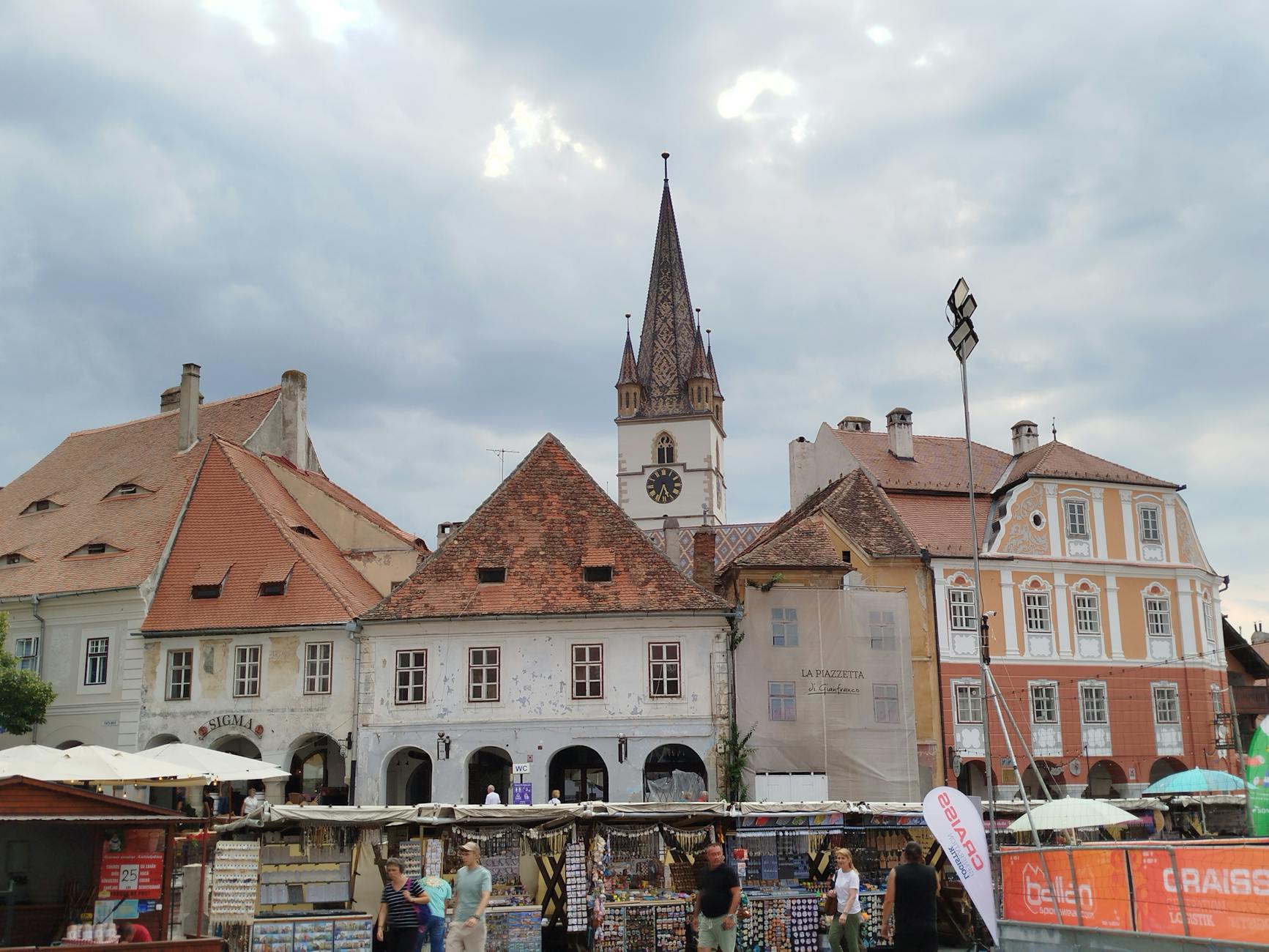 Rynek rumuńskiego miasteczka z kolorowymi straganami i wieżą zegarową