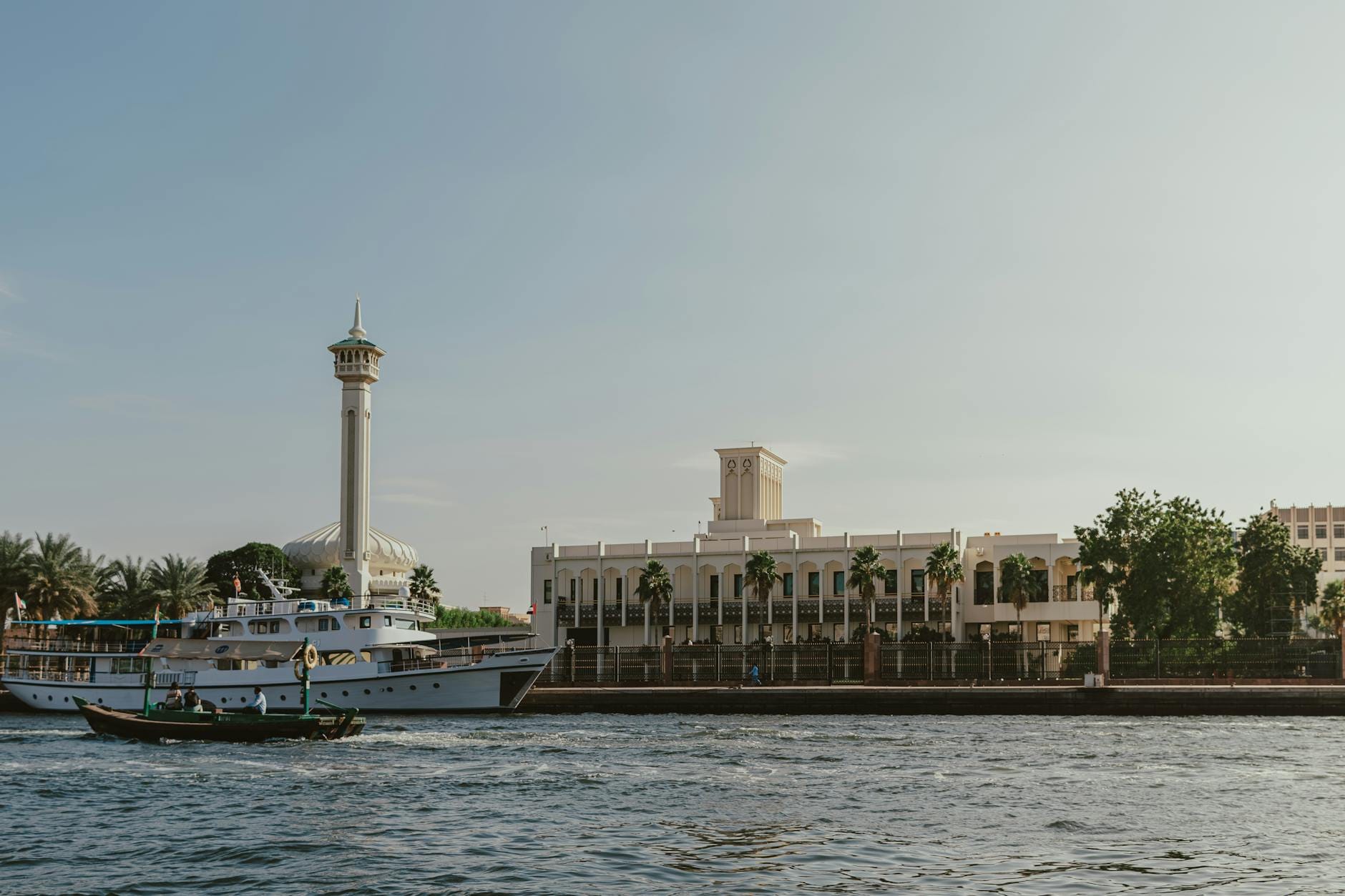 Tradycyjna dhow na wodach Dubai Creek z islamską zabudową w tle