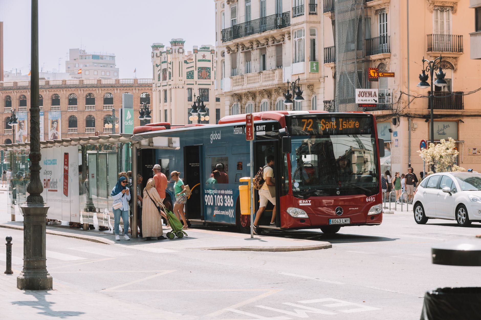 Ludzie wsiadają do miejskiego autobusu na przystanku w słonecznej Walencji