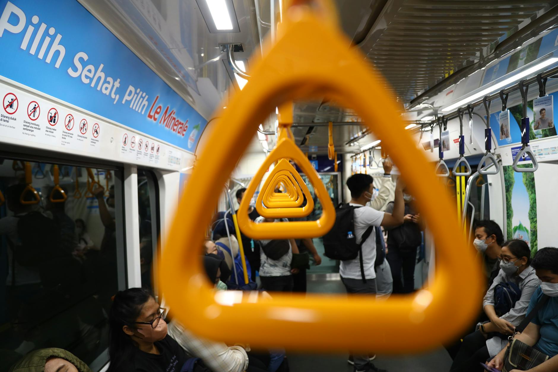 Pasażerowie w wagonie metra MRT w Dżakarcie trzymający się żółtych uchwytów