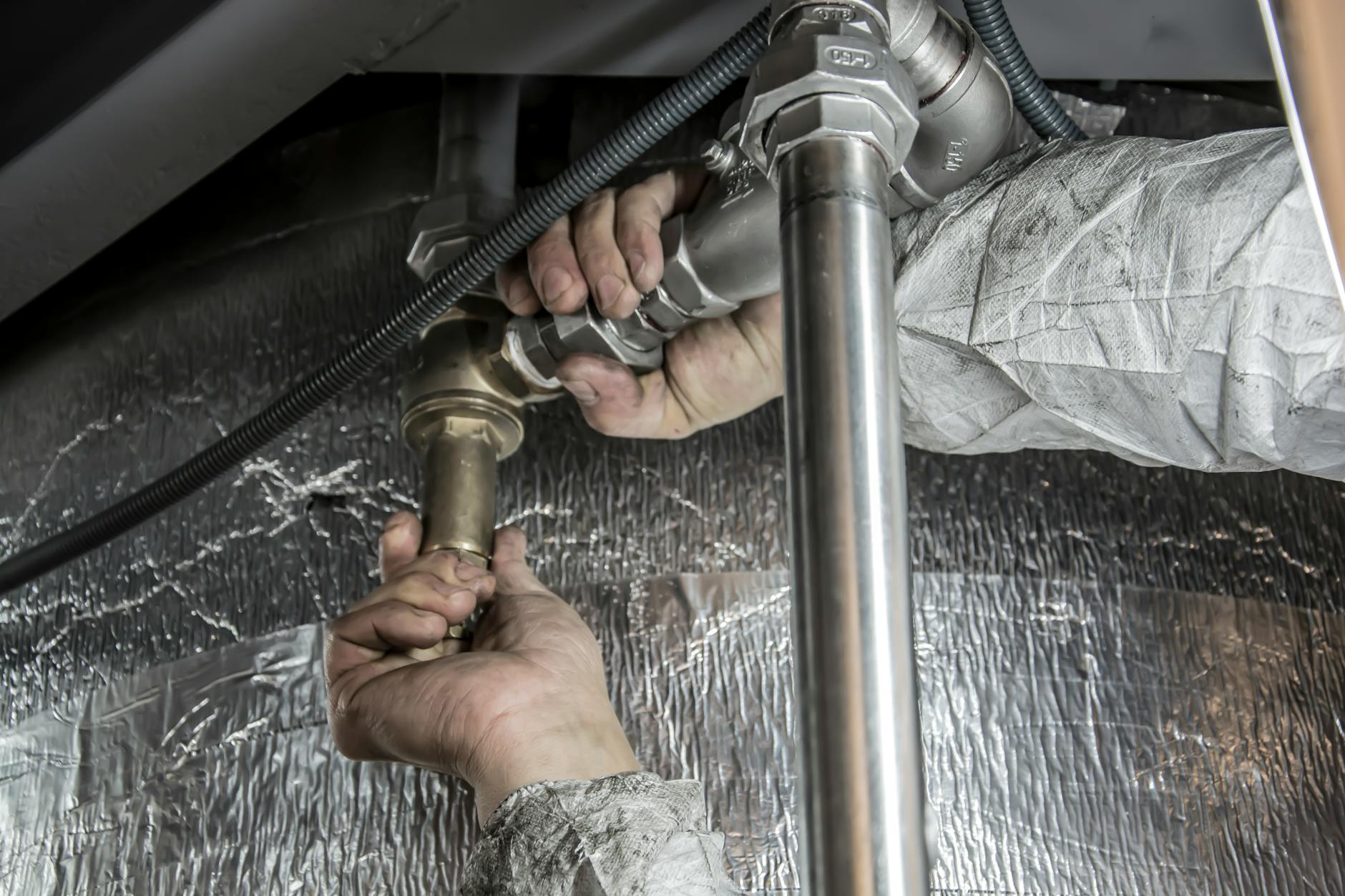 Ręce hydraulika montujące stalowe rury w domowej instalacji wodnej