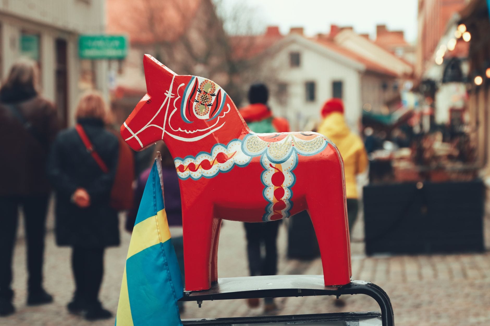 Tradycyjny czerwony konik Dala na tle szwedzkiej flagi w Göteborgu
