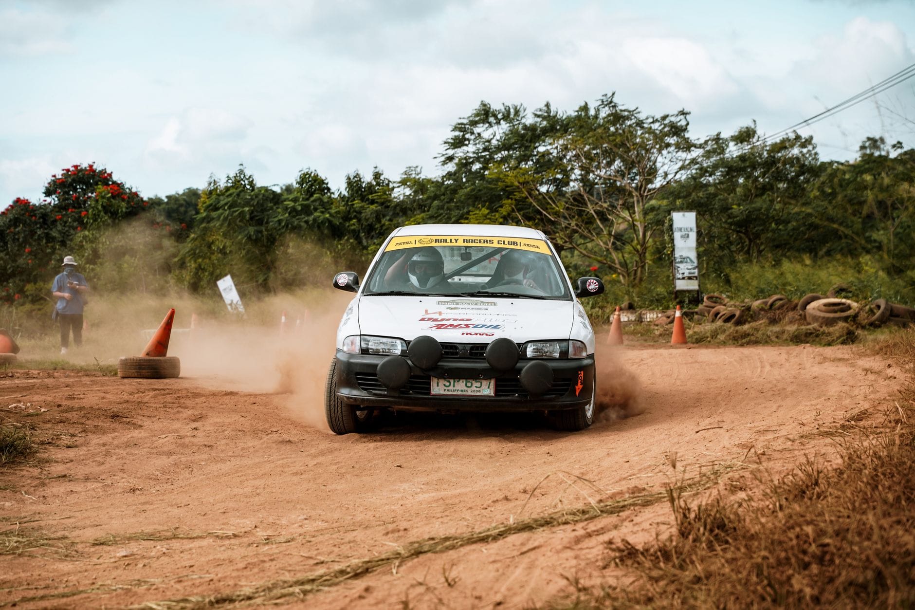 Samochód rajdowy pędzi po szutrowej, zakurzonej trasie off-roadowej